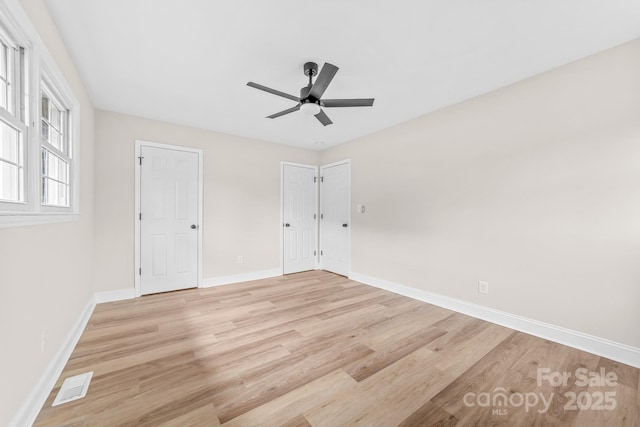 unfurnished bedroom featuring a ceiling fan, light wood-style flooring, baseboards, and visible vents