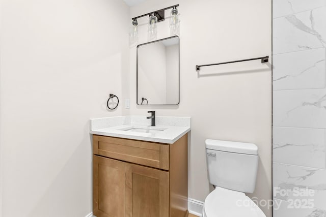 bathroom featuring baseboards, toilet, and vanity