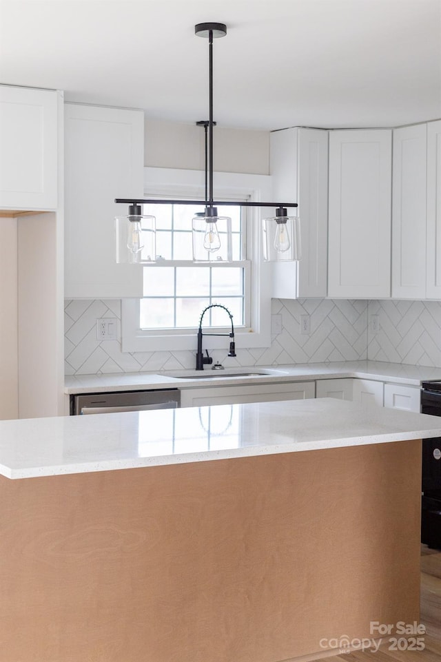 kitchen with backsplash, white cabinetry, stainless steel dishwasher, and a sink