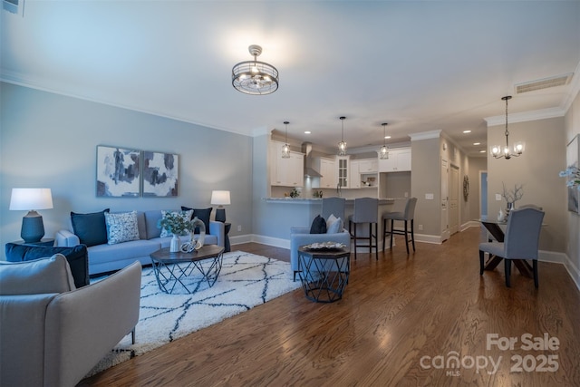 living room with dark wood-style floors, baseboards, visible vents, ornamental molding, and a notable chandelier