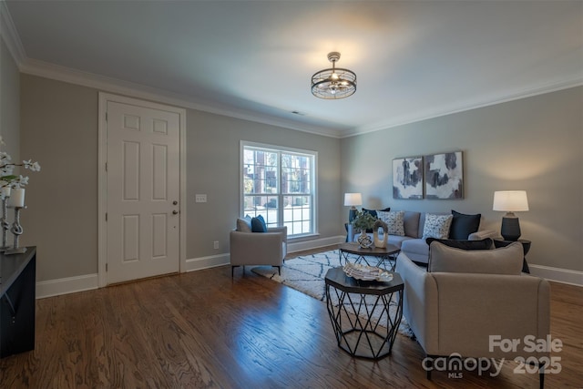 living area with an inviting chandelier, crown molding, wood finished floors, and baseboards