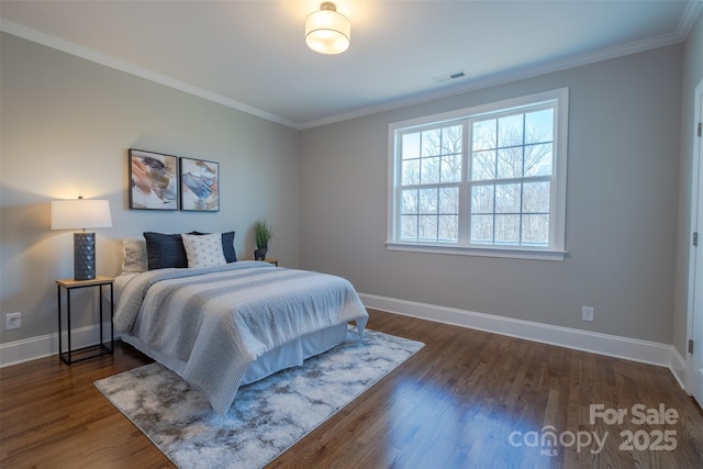 bedroom featuring baseboards, wood finished floors, visible vents, and ornamental molding