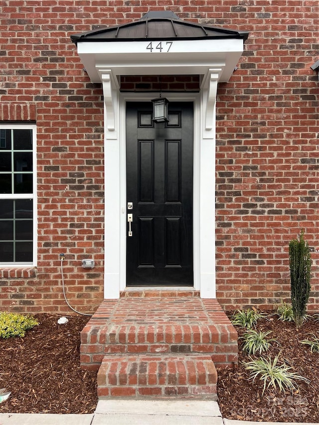 view of exterior entry featuring brick siding