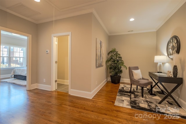 living area with visible vents, baseboards, attic access, ornamental molding, and wood finished floors