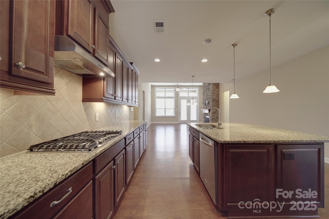 kitchen with visible vents, under cabinet range hood, a sink, appliances with stainless steel finishes, and decorative backsplash