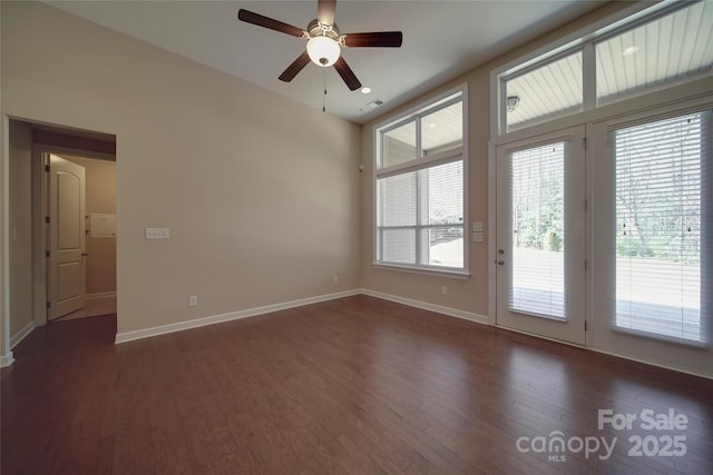 spare room with dark wood finished floors, a ceiling fan, and baseboards