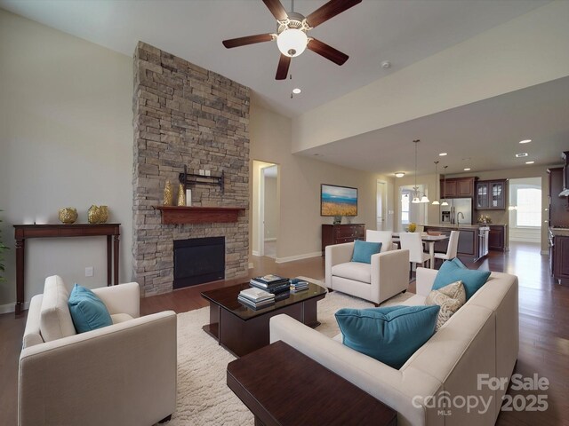 living area with recessed lighting, a stone fireplace, wood finished floors, and ceiling fan