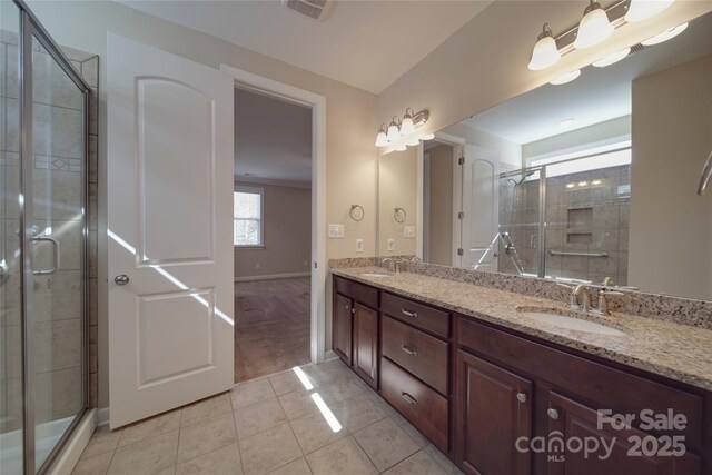 bathroom featuring tile patterned flooring, visible vents, a shower stall, and a sink