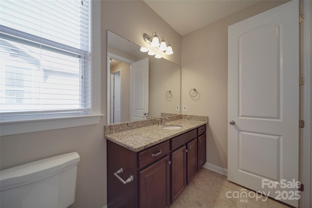 bathroom with toilet, vanity, and tile patterned flooring