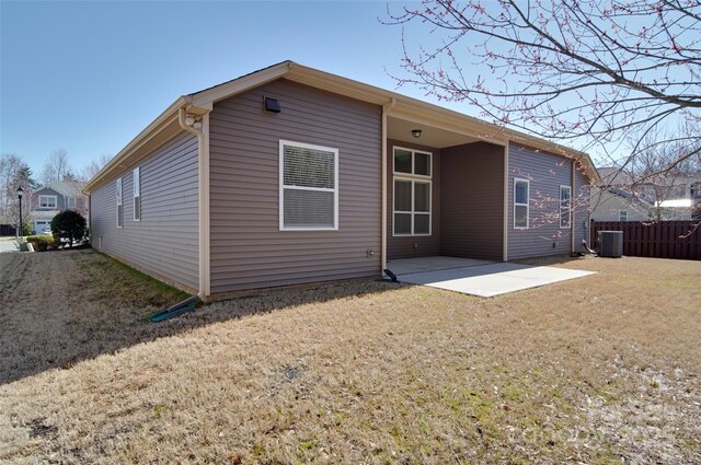 back of property with a yard, central air condition unit, fence, and a patio area