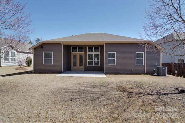 rear view of house with fence, roof with shingles, a lawn, cooling unit, and a patio