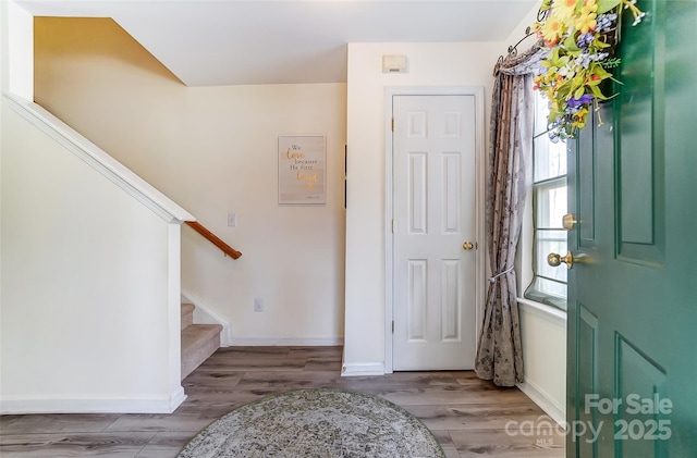 foyer with stairs, wood finished floors, and baseboards