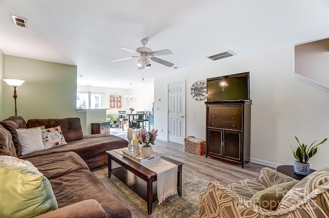 living room with visible vents, baseboards, ceiling fan, and light wood finished floors