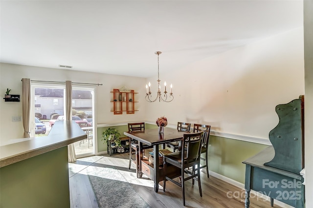 dining area with visible vents, baseboards, light wood-type flooring, and an inviting chandelier