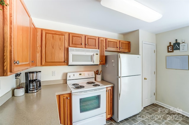 kitchen with white appliances, brown cabinetry, light countertops, and baseboards