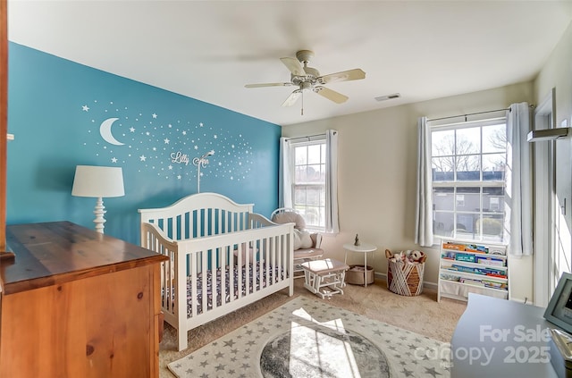 bedroom featuring visible vents, a crib, a ceiling fan, carpet flooring, and baseboards