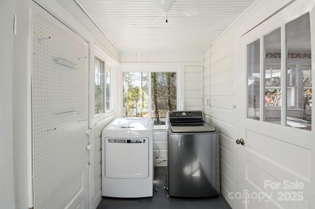 laundry area featuring wood walls, laundry area, and washing machine and clothes dryer