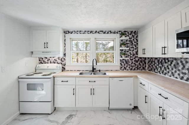 kitchen featuring under cabinet range hood, white cabinets, marble finish floor, white appliances, and a sink