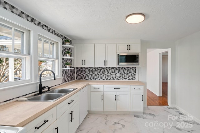 kitchen featuring stainless steel microwave, a sink, white cabinets, marble finish floor, and open shelves