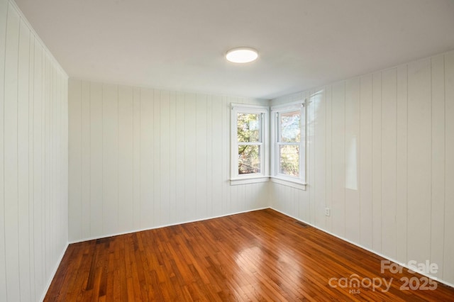 unfurnished room featuring visible vents and hardwood / wood-style flooring