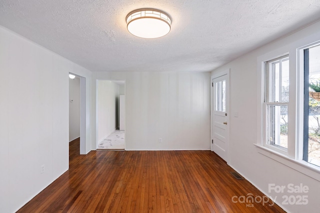 spare room featuring visible vents, wood-type flooring, and a textured ceiling