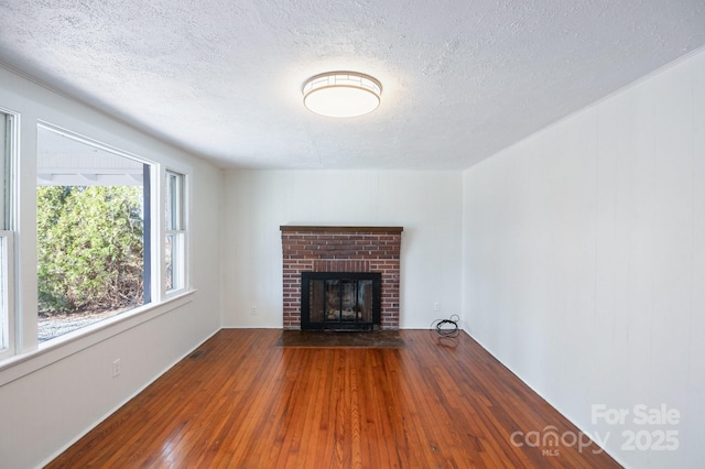 unfurnished living room featuring visible vents, a fireplace, a textured ceiling, and hardwood / wood-style flooring