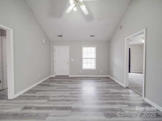 unfurnished room with visible vents, light wood-style flooring, ceiling fan, and vaulted ceiling