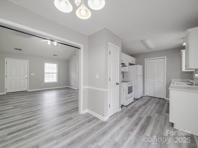 kitchen with white appliances, visible vents, a sink, light countertops, and white cabinets