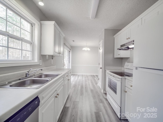 kitchen with white appliances, a sink, light countertops, white cabinets, and under cabinet range hood