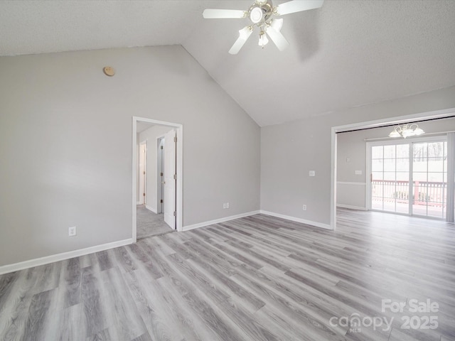 unfurnished room featuring ceiling fan with notable chandelier, light wood-style flooring, baseboards, and vaulted ceiling