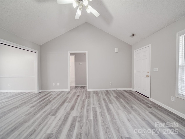 unfurnished living room featuring visible vents, baseboards, lofted ceiling, light wood-style floors, and a ceiling fan