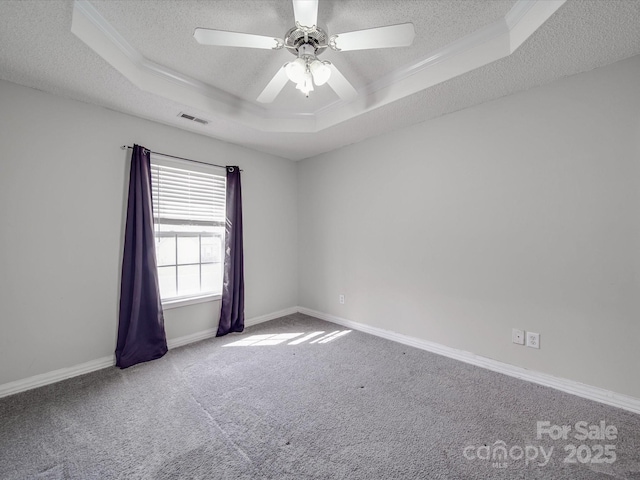 carpeted empty room featuring visible vents, a ceiling fan, a tray ceiling, a textured ceiling, and baseboards