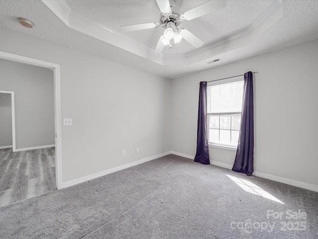 carpeted spare room featuring a tray ceiling, a textured ceiling, visible vents, and a ceiling fan