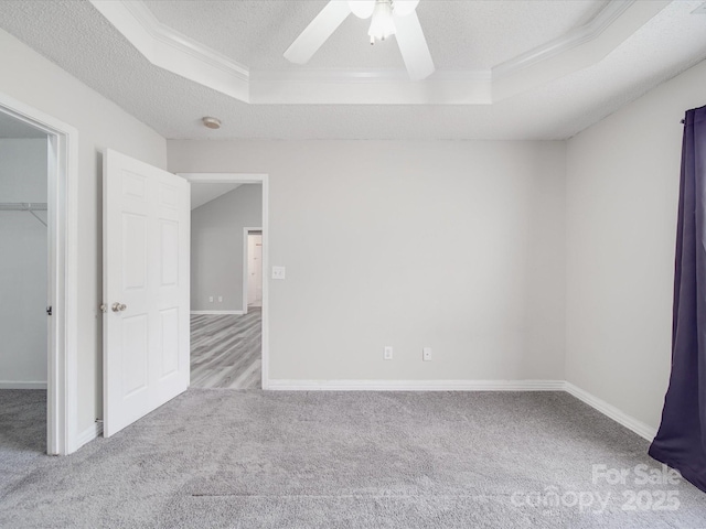 unfurnished room with a raised ceiling, a textured ceiling, and carpet flooring