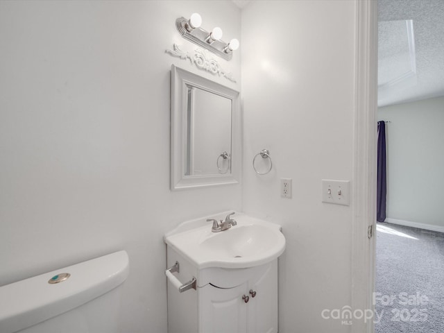 half bathroom with a textured ceiling, toilet, and vanity