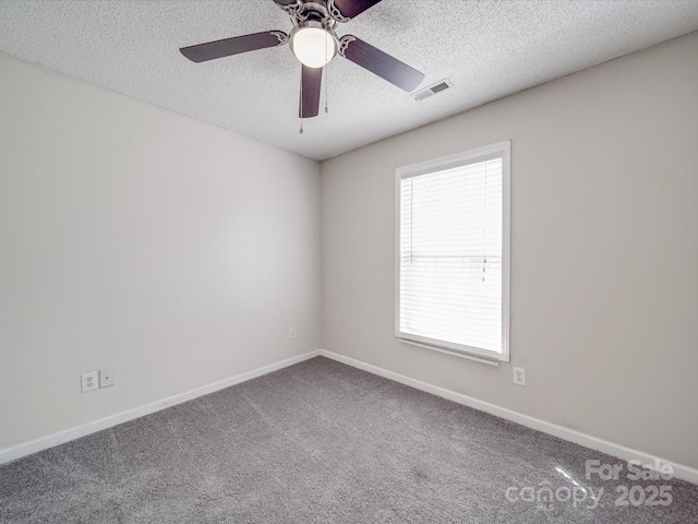 carpeted spare room with ceiling fan, baseboards, visible vents, and a textured ceiling