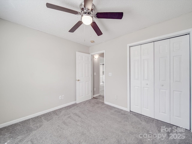 unfurnished bedroom with a ceiling fan, baseboards, carpet floors, a closet, and a textured ceiling