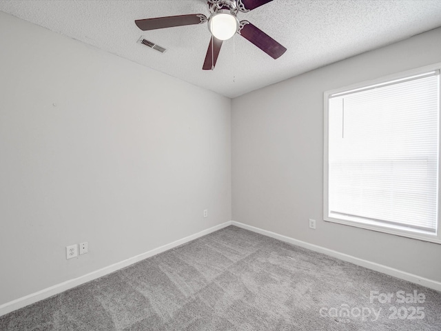 carpeted empty room featuring baseboards, visible vents, a textured ceiling, and a ceiling fan