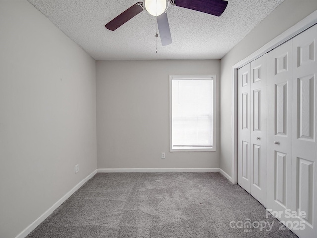 unfurnished bedroom featuring carpet, baseboards, a closet, and a textured ceiling