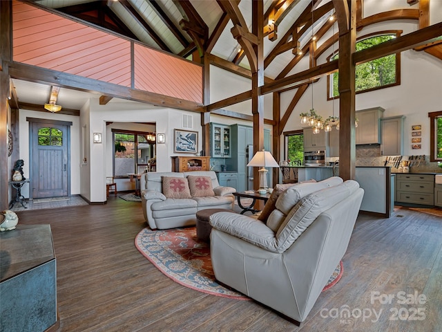 living area featuring an inviting chandelier, wood finished floors, vaulted ceiling with beams, and a healthy amount of sunlight