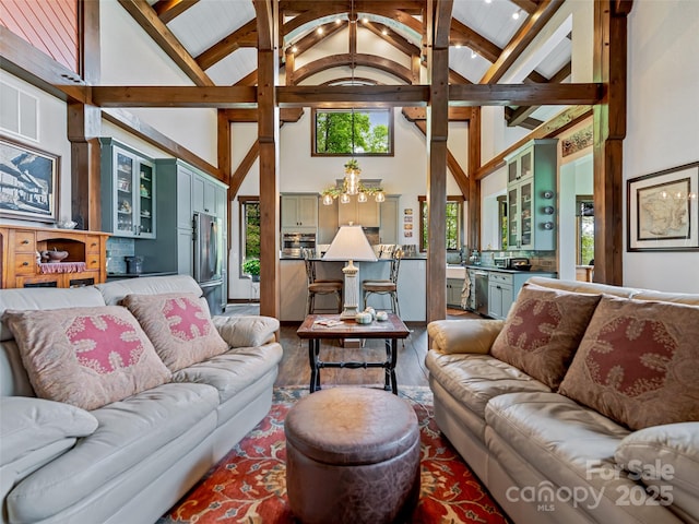 living area with beamed ceiling, wood finished floors, and high vaulted ceiling