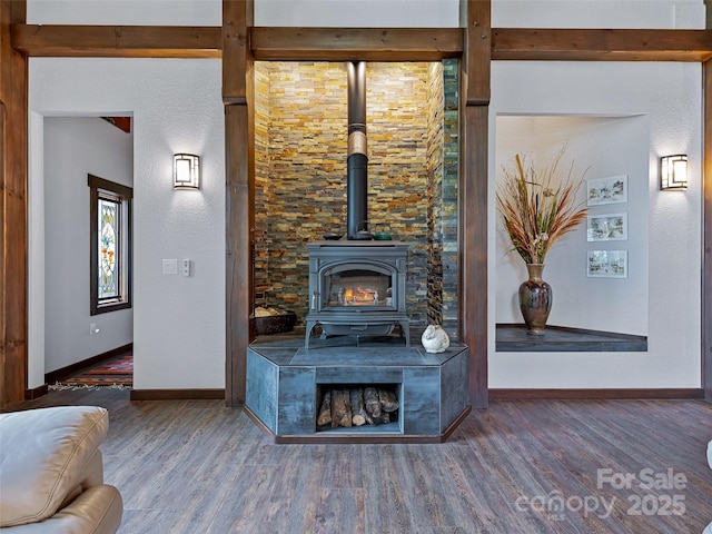 unfurnished living room with baseboards, wood finished floors, and a wood stove