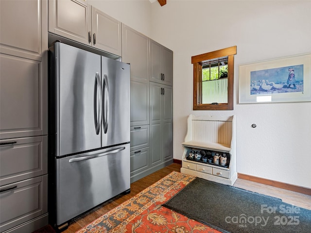 kitchen with dark wood-style floors, gray cabinetry, freestanding refrigerator, and baseboards