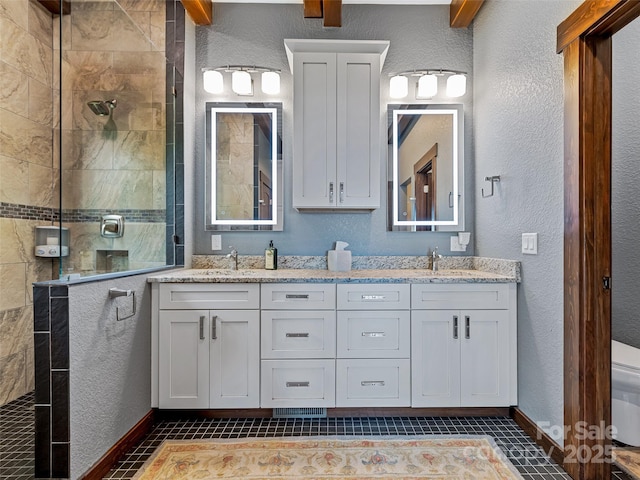 bathroom featuring double vanity, a walk in shower, a textured wall, and a sink