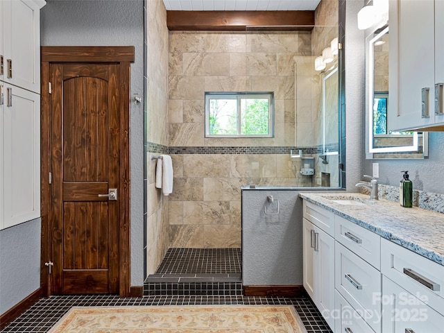 bathroom with tile patterned flooring, walk in shower, vanity, and a textured wall