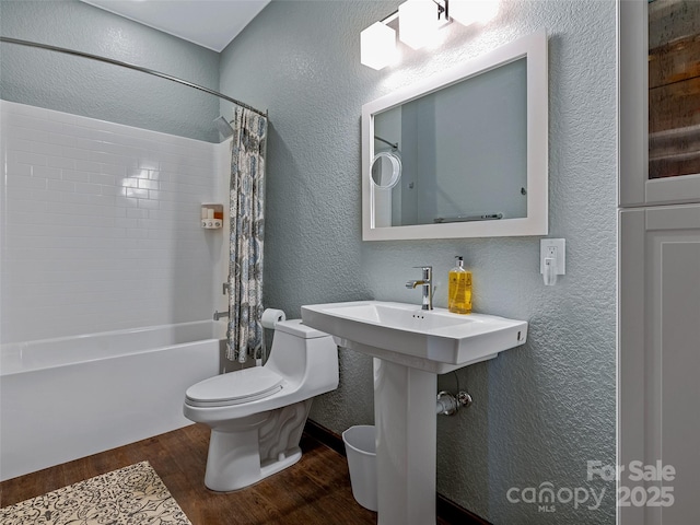 full bath featuring toilet, shower / tub combo, a textured wall, and wood finished floors