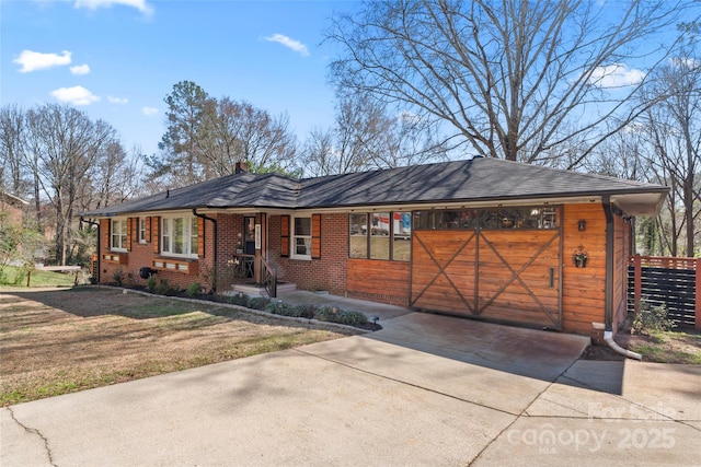 ranch-style home with a front yard, an attached garage, a shingled roof, concrete driveway, and brick siding