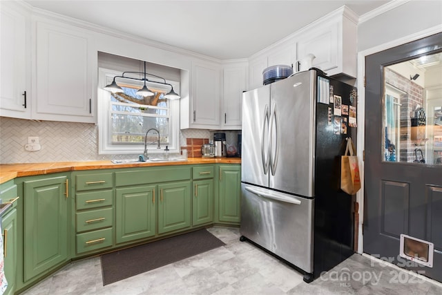 kitchen featuring backsplash, butcher block countertops, freestanding refrigerator, white cabinets, and a sink