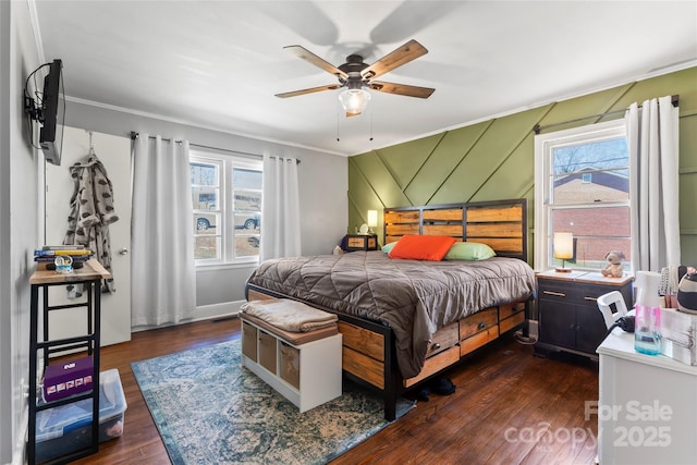 bedroom featuring dark wood finished floors, multiple windows, ceiling fan, and ornamental molding