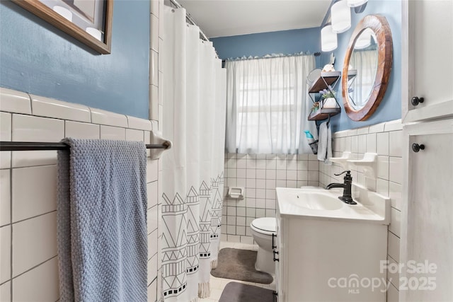 full bath with a shower with curtain, toilet, tile walls, wainscoting, and vanity